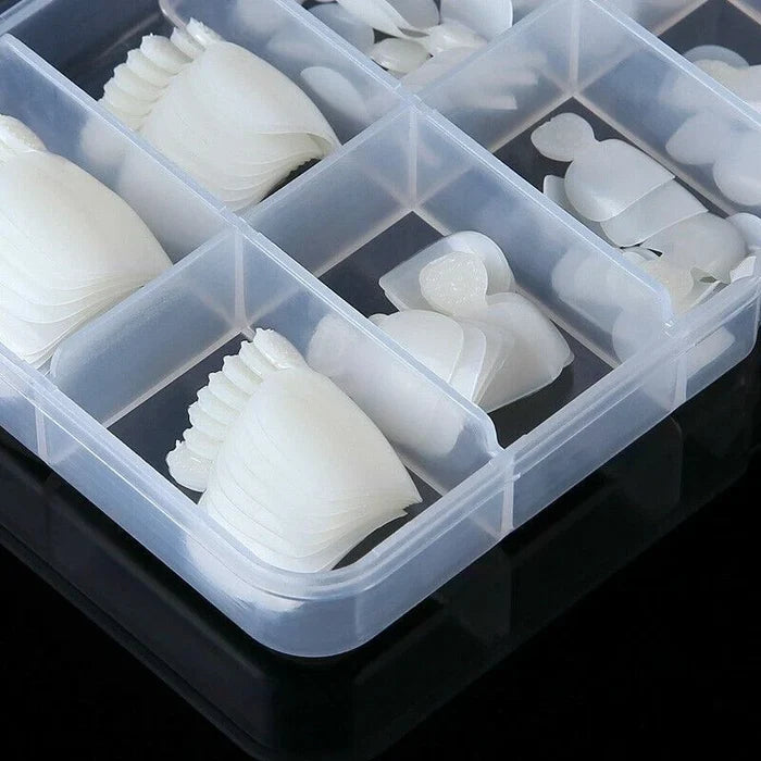 A clear plastic organizer tray with multiple compartments holding small white silicone or rubber pieces, photographed on a black reflective surface.